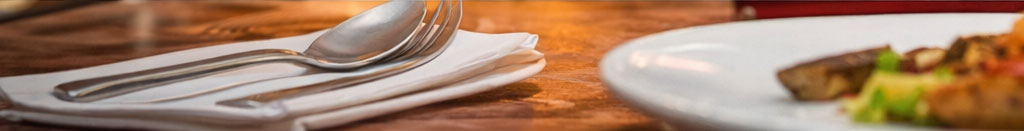 Host a dinner footer image A sliver of a table showing a place setting.